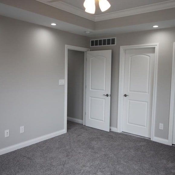 unfurnished bedroom with ornamental molding and dark colored carpet