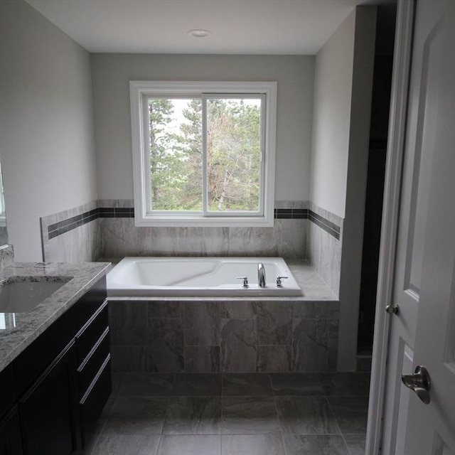 bathroom featuring vanity and tiled tub