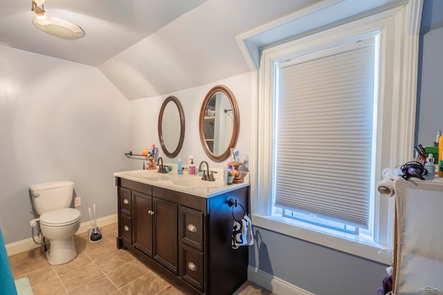 bathroom with tile patterned flooring, vanity, toilet, and vaulted ceiling