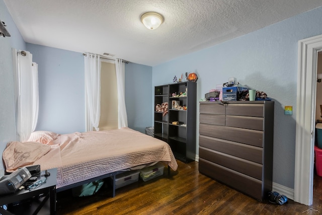 bedroom with a textured ceiling and dark hardwood / wood-style floors