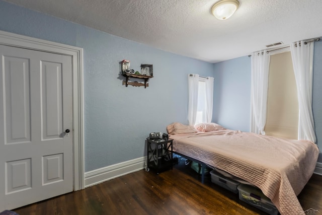 bedroom with dark hardwood / wood-style floors and a textured ceiling