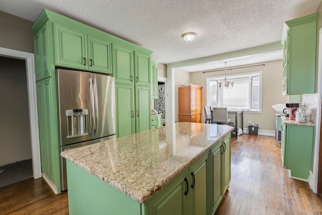 kitchen featuring light stone countertops, stainless steel refrigerator with ice dispenser, dark hardwood / wood-style flooring, a kitchen island, and hanging light fixtures