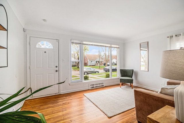 foyer entrance featuring crown molding and light hardwood / wood-style flooring