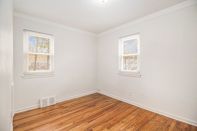 spare room featuring ornamental molding and light hardwood / wood-style flooring