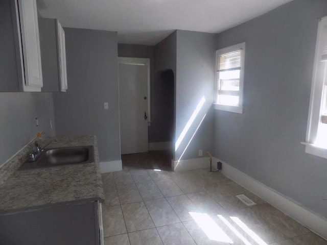 6334 Tuxedo Ave, Detroit, MI 48204 - kitchen with a sink, baseboards, white cabinetry, light tile patterned flooring, and light countertops