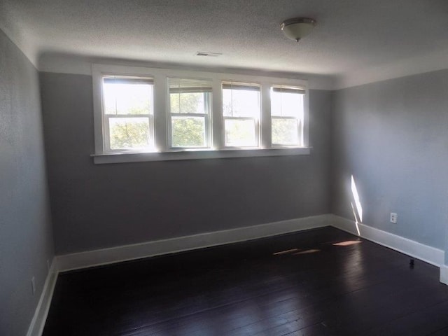 unfurnished room with a textured ceiling and dark hardwood / wood-style floors