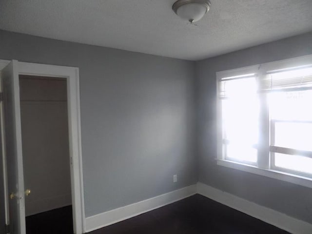 unfurnished bedroom featuring a closet, a textured ceiling, and multiple windows