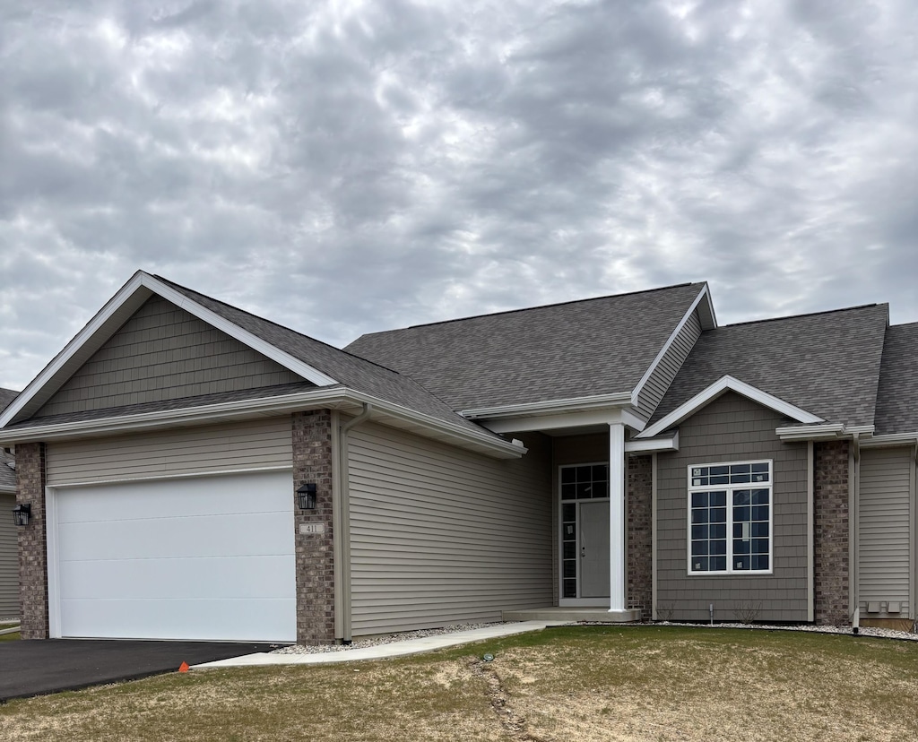 ranch-style house featuring a garage, aphalt driveway, and roof with shingles