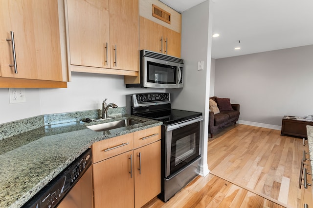 kitchen with light brown cabinets, sink, light hardwood / wood-style flooring, stone countertops, and stainless steel appliances