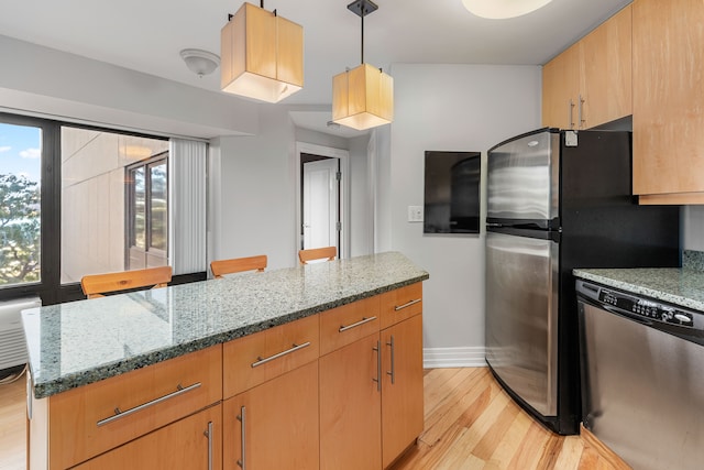 kitchen with light stone countertops, appliances with stainless steel finishes, decorative light fixtures, a kitchen island, and light wood-type flooring