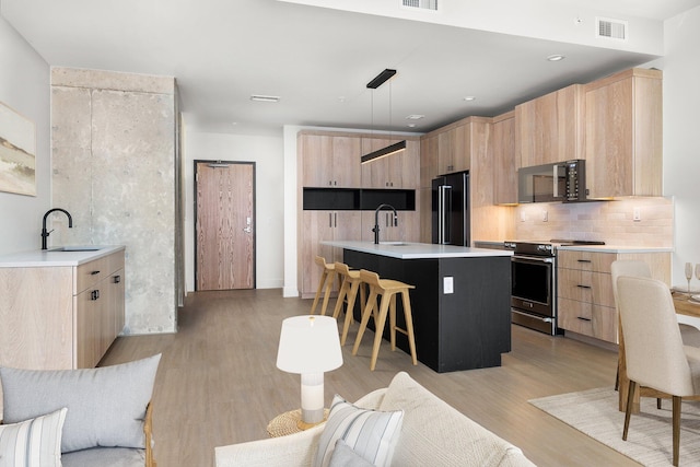 kitchen with sink, black fridge, decorative light fixtures, a center island, and stainless steel electric stove