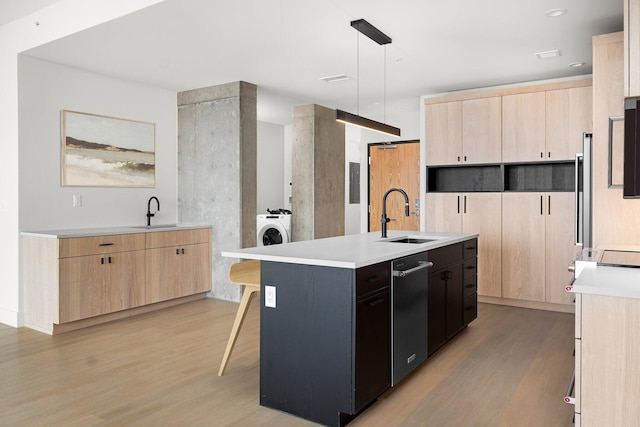 kitchen featuring sink, hanging light fixtures, a kitchen breakfast bar, an island with sink, and light wood-type flooring