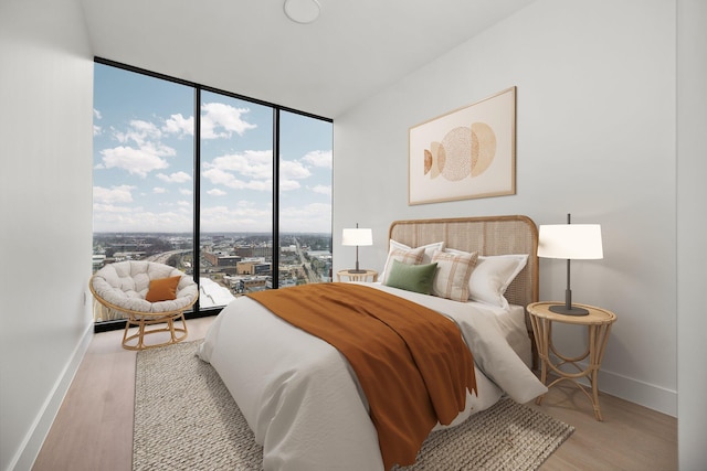 bedroom featuring access to exterior, a wall of windows, and light hardwood / wood-style floors