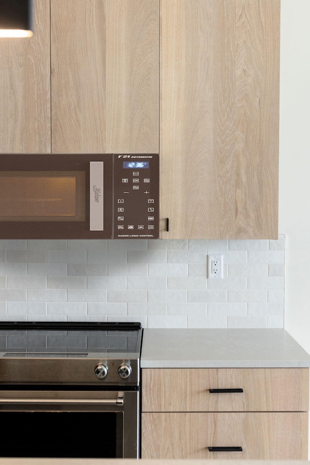 room details with tasteful backsplash, light brown cabinetry, and electric range