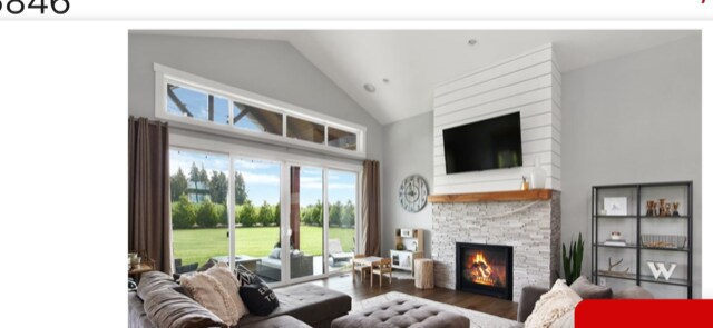 living room featuring lofted ceiling, a fireplace, and dark wood-type flooring