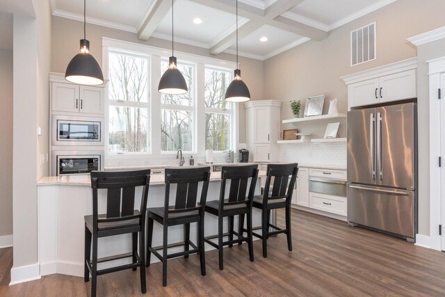 kitchen featuring appliances with stainless steel finishes, light stone counters, tasteful backsplash, white cabinets, and beamed ceiling