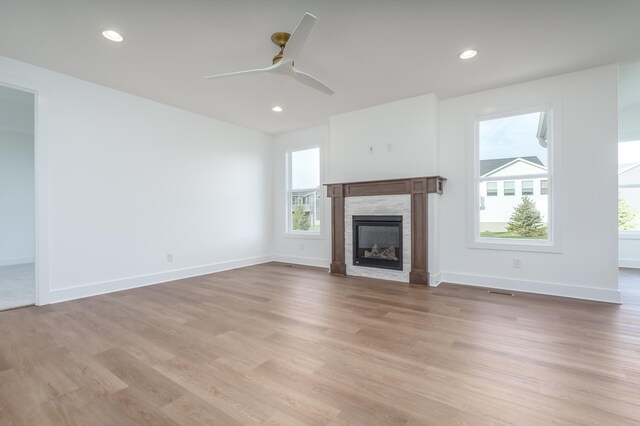 unfurnished living room featuring ceiling fan, a fireplace, and light wood-type flooring