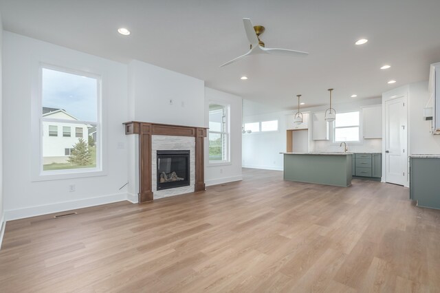 unfurnished living room with ceiling fan, sink, and light hardwood / wood-style floors