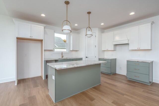 kitchen featuring sink, white cabinetry, hanging light fixtures, a kitchen island, and light hardwood / wood-style floors