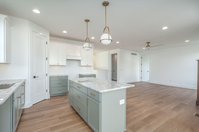 kitchen with decorative light fixtures, a center island, ceiling fan, light hardwood / wood-style floors, and white cabinets