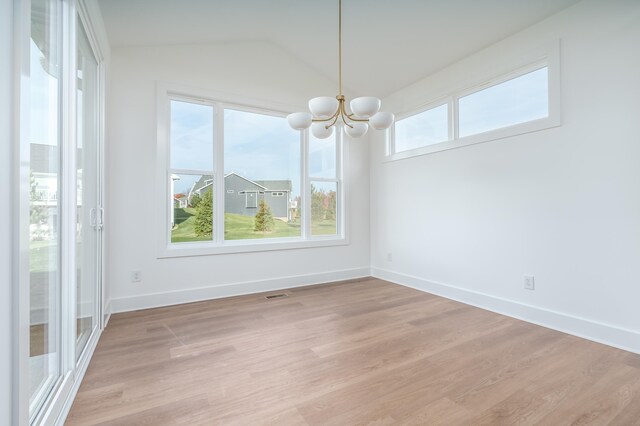 unfurnished dining area with an inviting chandelier, vaulted ceiling, and light wood-type flooring