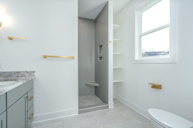 bathroom featuring vanity, tiled shower, and toilet