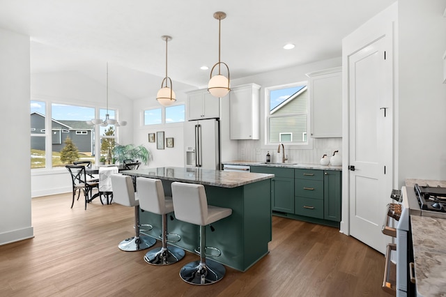 kitchen with sink, high end appliances, white cabinetry, decorative light fixtures, and green cabinets