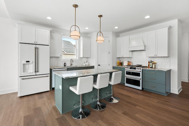 kitchen featuring high end appliances, decorative light fixtures, a kitchen island, custom range hood, and white cabinets