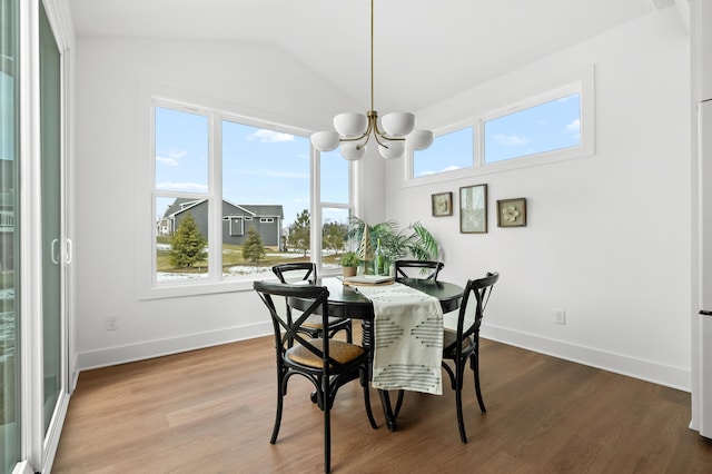 dining space featuring hardwood / wood-style flooring, lofted ceiling, and a notable chandelier