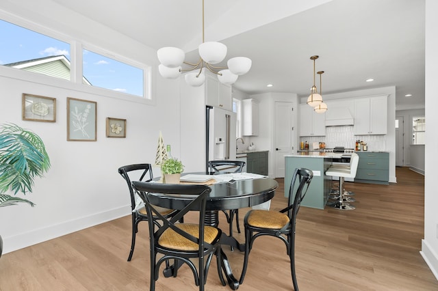 dining space with light hardwood / wood-style floors and a notable chandelier