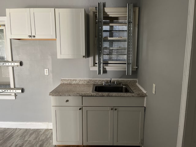 kitchen with hardwood / wood-style flooring, white cabinetry, and sink