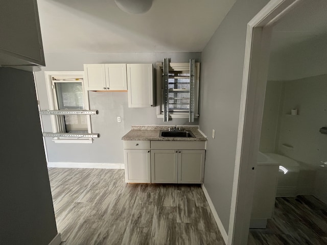 kitchen with dark hardwood / wood-style flooring, white cabinetry, and sink