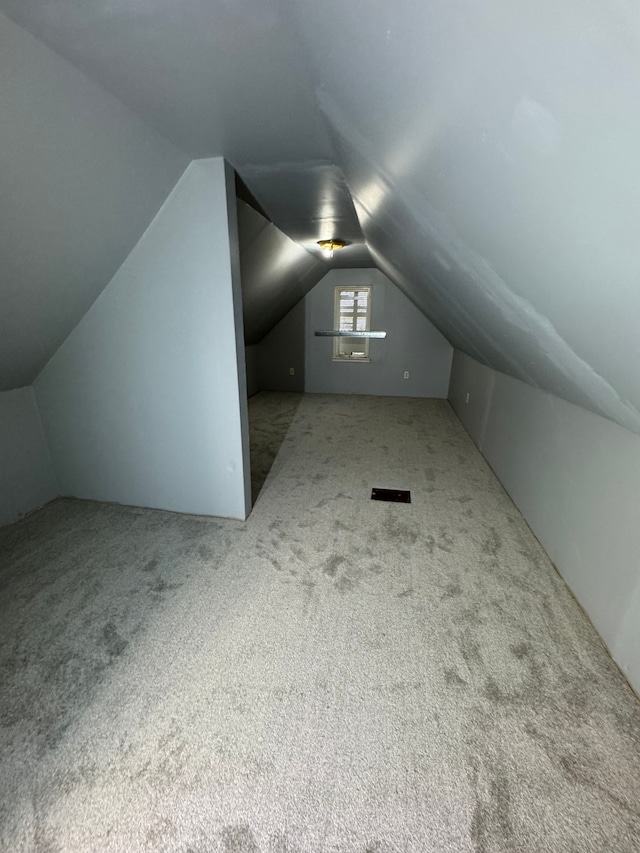 bonus room with lofted ceiling and light carpet