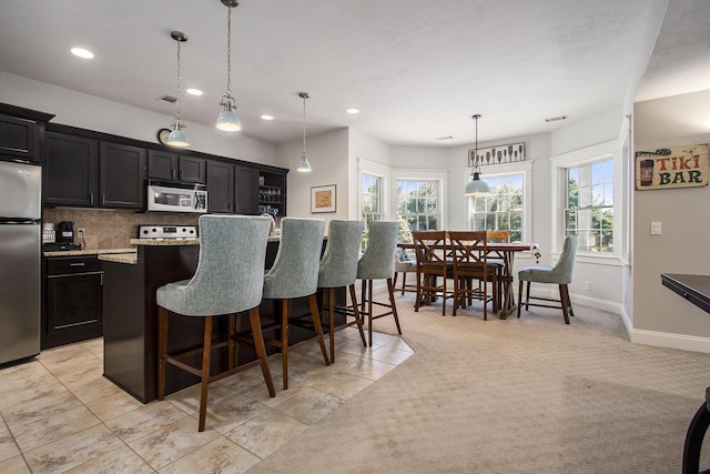 3975 Harbor Breeze Dr, Norton Shores, MI 49441 - kitchen featuring stainless steel appliances, healthy amount of natural light, recessed lighting, a kitchen breakfast bar, and an island with sink
