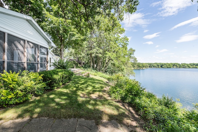 view of yard featuring a sunroom and a water view