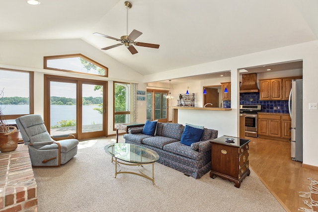 living room with ceiling fan, light hardwood / wood-style floors, a water view, and lofted ceiling