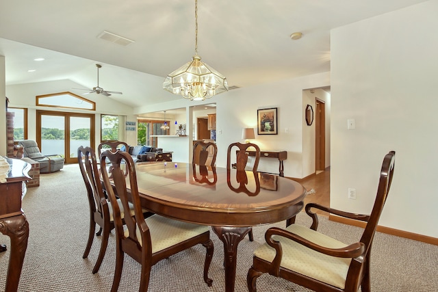 carpeted dining room with ceiling fan with notable chandelier and lofted ceiling