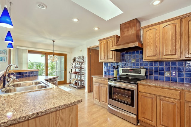 kitchen with electric range, sink, wall chimney range hood, light hardwood / wood-style flooring, and a notable chandelier