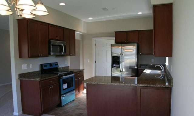 kitchen featuring dark stone counters, stainless steel appliances, sink, decorative light fixtures, and a chandelier