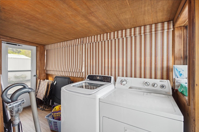 laundry room featuring wooden walls, washer and clothes dryer, wood ceiling, and light hardwood / wood-style floors