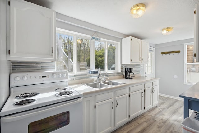 kitchen featuring decorative backsplash, light wood-type flooring, white electric range oven, sink, and white cabinets