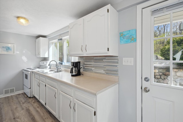 kitchen with range, sink, tasteful backsplash, light hardwood / wood-style floors, and white cabinetry