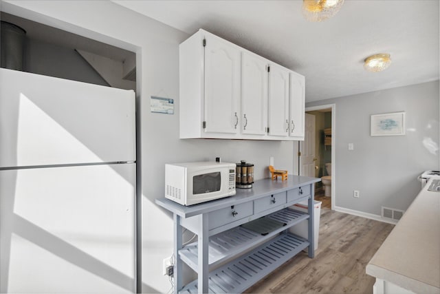 kitchen with white cabinets, white appliances, and light hardwood / wood-style flooring