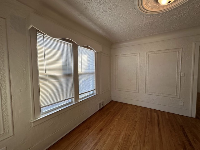 unfurnished room featuring hardwood / wood-style flooring and a textured ceiling