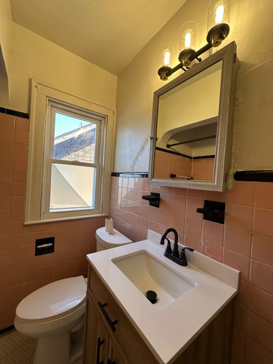 bathroom featuring vanity, tile walls, and toilet