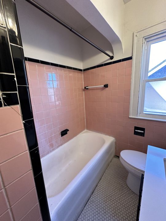 bathroom with tiled shower / bath combo, tile walls, and toilet