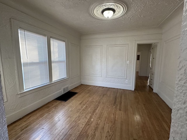 empty room with hardwood / wood-style floors and a textured ceiling