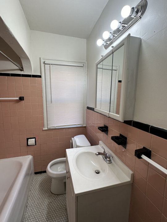 bathroom featuring tile patterned floors, vanity, toilet, and tile walls