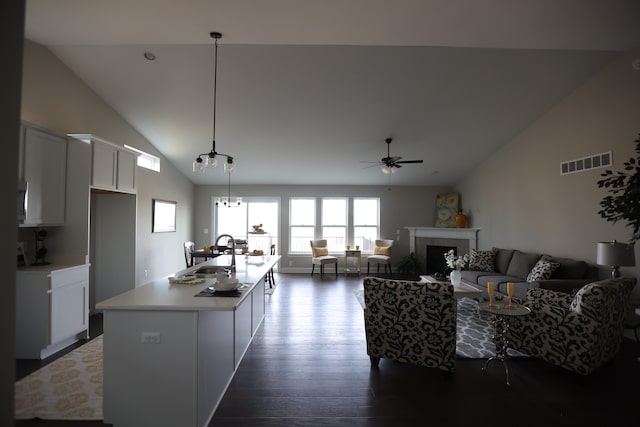 kitchen with a tile fireplace, sink, pendant lighting, a center island with sink, and white cabinets