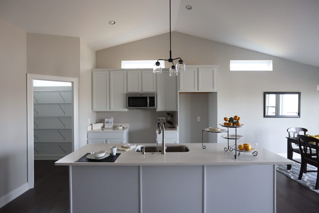 kitchen featuring sink, an island with sink, lofted ceiling, decorative light fixtures, and white cabinets